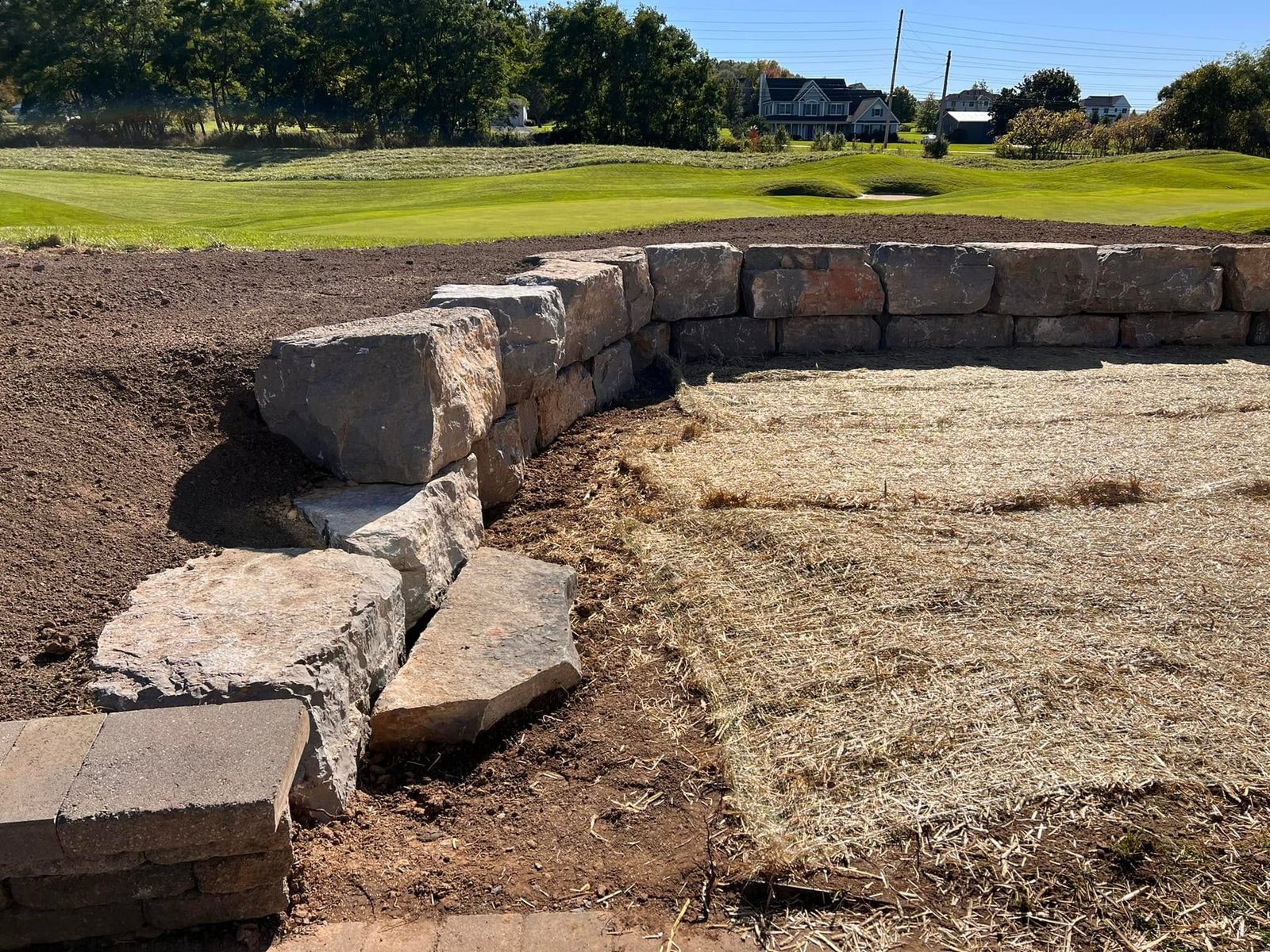 Large natural stone retaining wall with stone steps along a graded slope